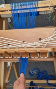 Blue threads pulled under tension while being rolled on to the loom.