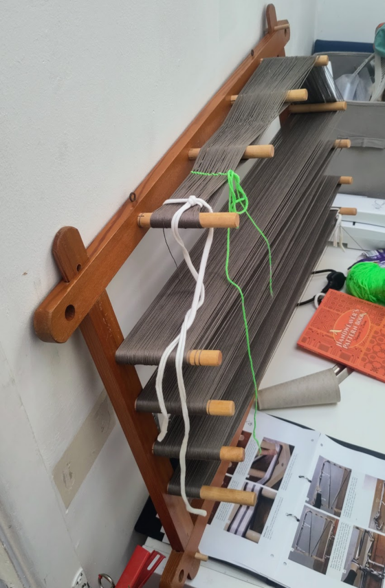 Grey yarn on a wooden warping board.