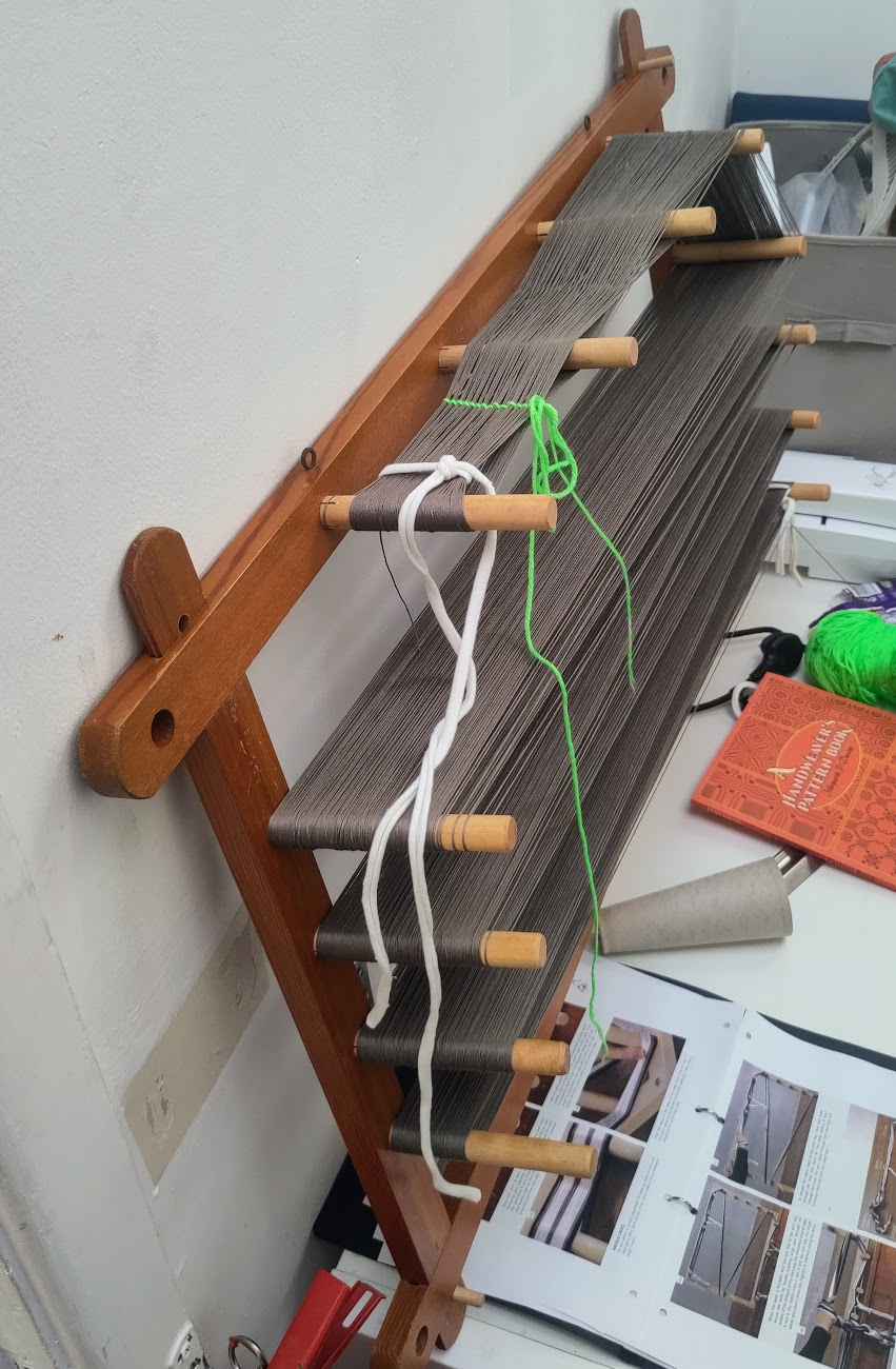 Grey yarn on a wooden warping board.