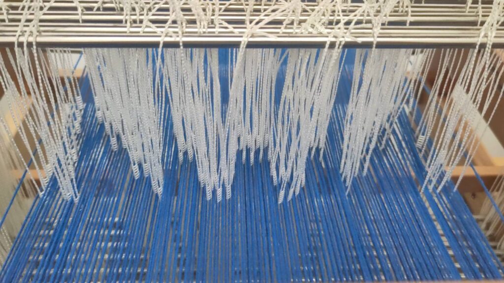 The finished threading, where the pattern of the grid can be made out in the arrangement of string heddles.